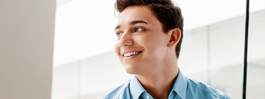 A young, male intern smiles in a conference room setting. (mobile)